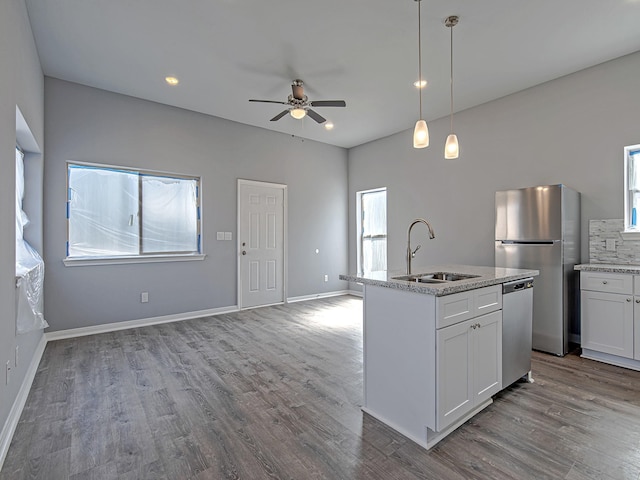 kitchen featuring stainless steel appliances, open floor plan, a sink, and wood finished floors