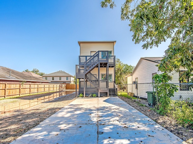 back of house with a fenced backyard, stairs, and a wooden deck