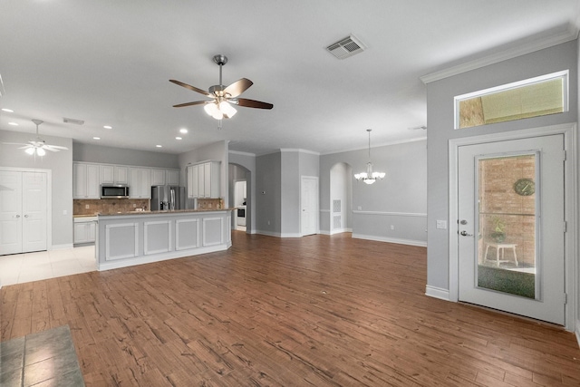 unfurnished living room featuring light wood-type flooring, visible vents, arched walkways, and ceiling fan with notable chandelier