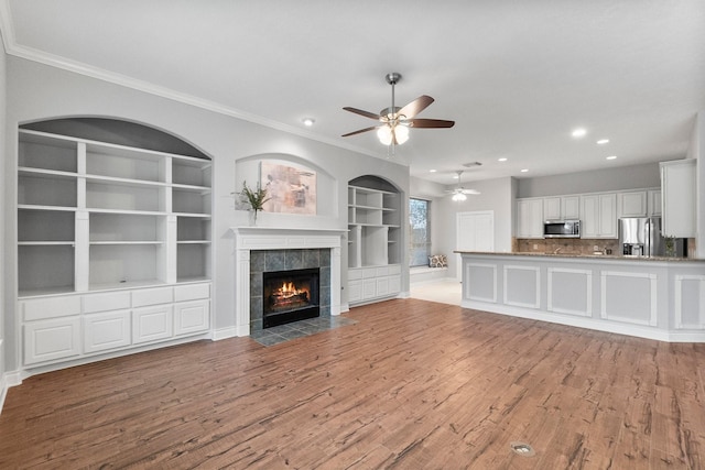 unfurnished living room with ornamental molding, a fireplace, and wood finished floors