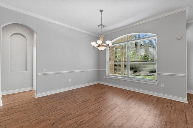 unfurnished room with baseboards, visible vents, ornamental molding, wood finished floors, and an inviting chandelier