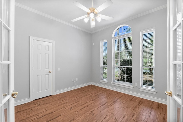 empty room with ornamental molding, a ceiling fan, french doors, and wood finished floors