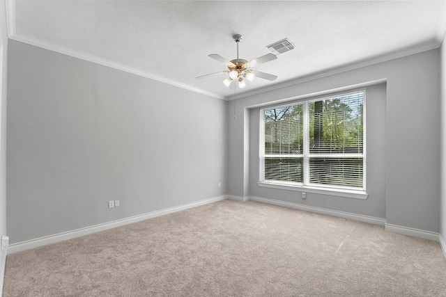 carpeted spare room featuring ornamental molding, visible vents, ceiling fan, and baseboards