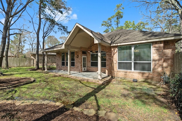 back of property featuring brick siding, a lawn, a patio area, and fence