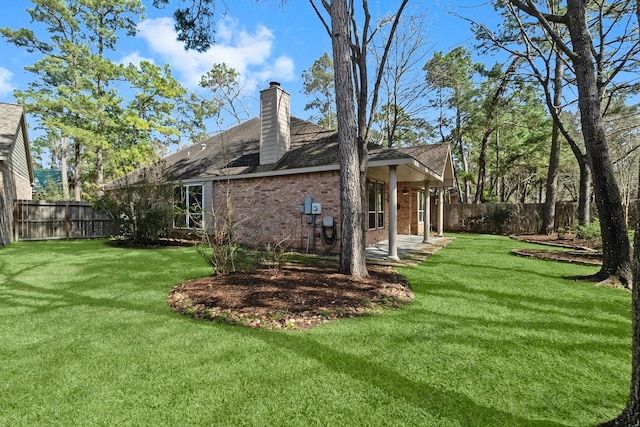 view of side of home with a fenced backyard, a chimney, a lawn, and brick siding