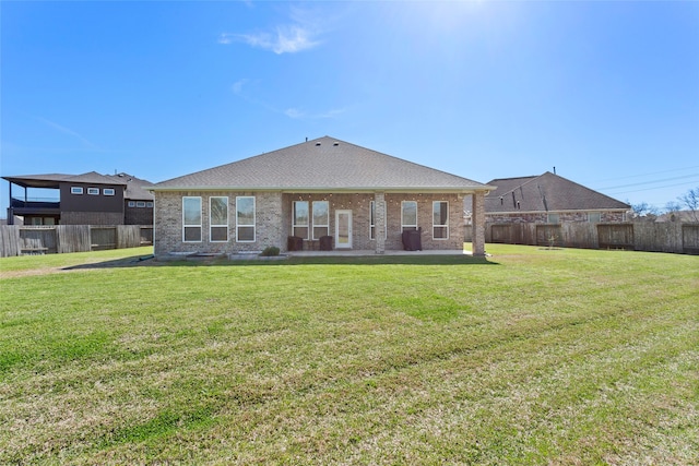 back of house with brick siding, a lawn, and a fenced backyard