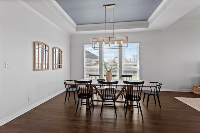 dining space with dark wood-style floors, a raised ceiling, and baseboards