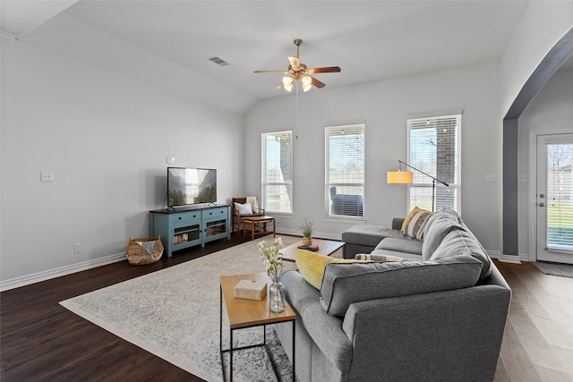 living room with arched walkways, visible vents, baseboards, and wood finished floors