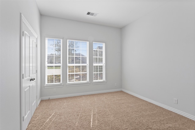 carpeted spare room with visible vents and baseboards