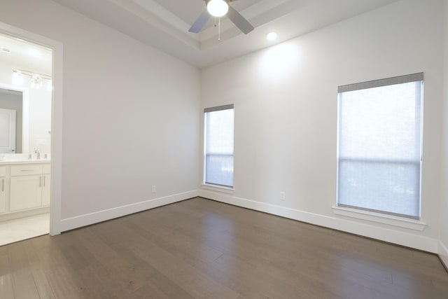 spare room featuring a ceiling fan, baseboards, a raised ceiling, and wood finished floors