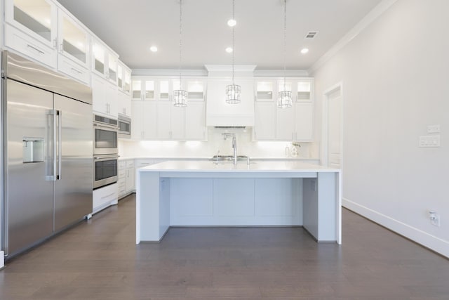 kitchen featuring light countertops, a kitchen island with sink, visible vents, and built in appliances