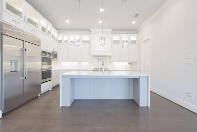 35 Papado Trails Cir, The Woodlands, TX 77375 - kitchen with built in appliances, a center island with sink, light countertops, decorative light fixtures, and ornamental molding