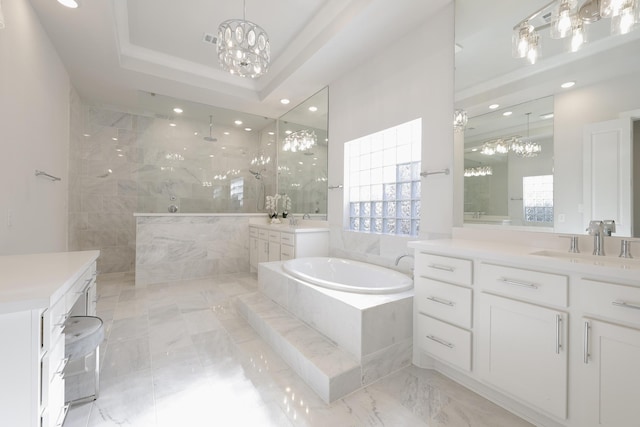 bathroom with an inviting chandelier, a tray ceiling, walk in shower, and a bath