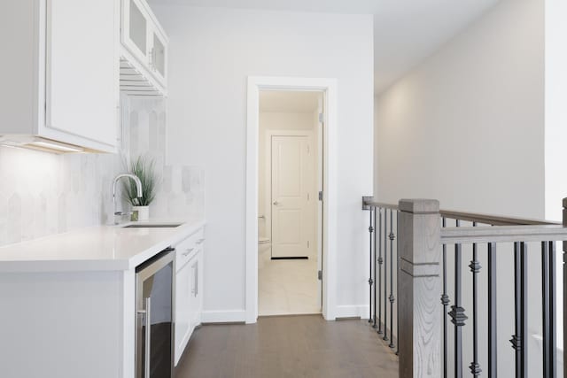 kitchen featuring light countertops, wine cooler, a sink, and white cabinetry