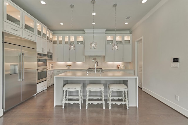 35 Papado Trails Cir, The Woodlands, TX 77375 - kitchen featuring built in appliances, light countertops, an island with sink, a kitchen bar, and white cabinetry
