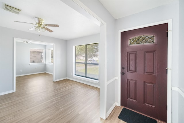 entrance foyer with baseboards, ceiling fan, visible vents, and light wood-style floors