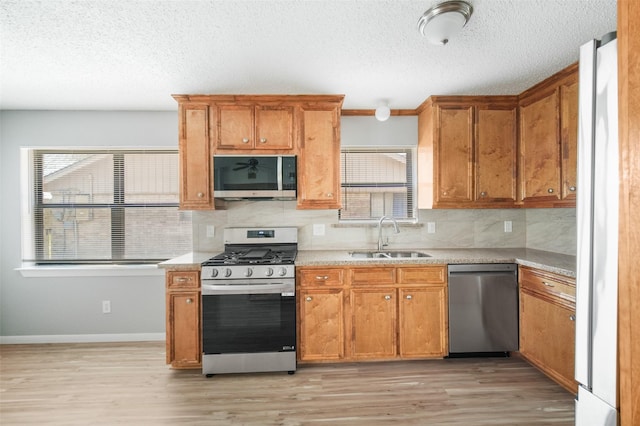 kitchen with light countertops, appliances with stainless steel finishes, a sink, and a wealth of natural light