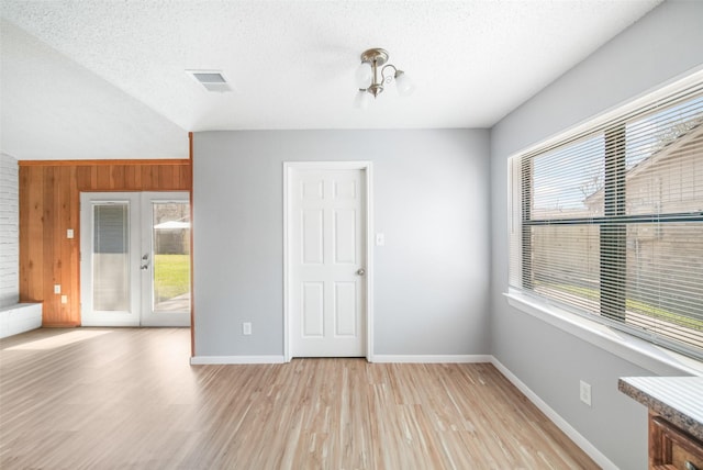 spare room with baseboards, visible vents, a textured ceiling, french doors, and light wood-type flooring