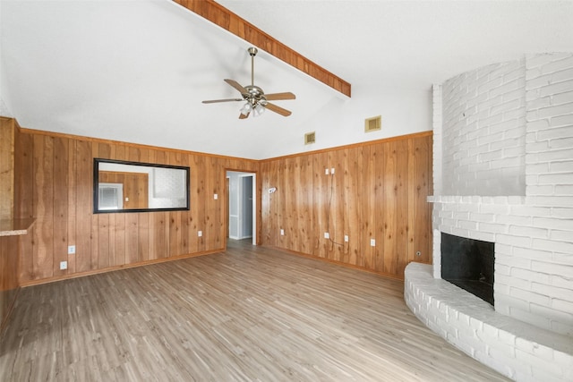 unfurnished living room featuring vaulted ceiling with beams, a fireplace, wood finished floors, and visible vents