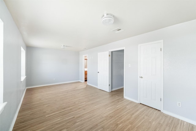 empty room featuring visible vents, light wood-style flooring, and baseboards