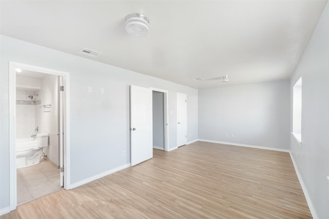 interior space with baseboards, connected bathroom, visible vents, and light wood-style floors