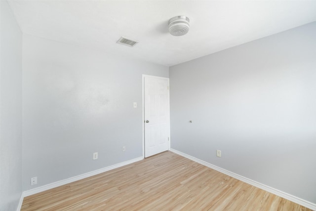 empty room featuring light wood-style flooring, visible vents, and baseboards