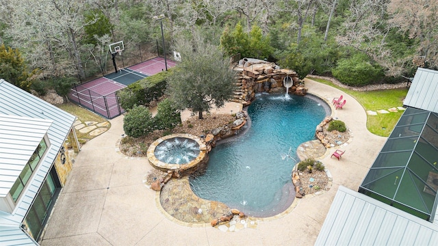 view of pool with fence and a pool with connected hot tub