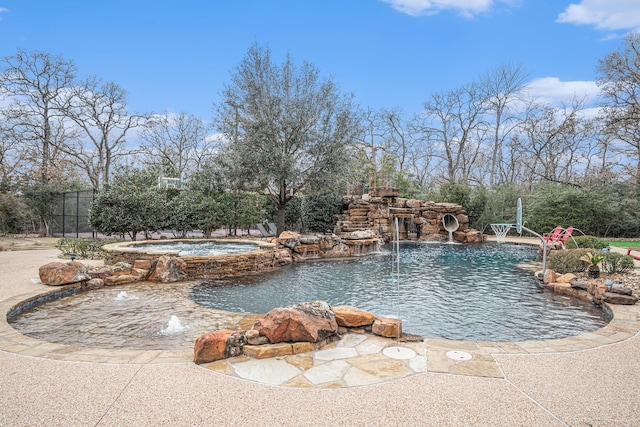 view of swimming pool featuring a small pond, fence, and a pool with connected hot tub