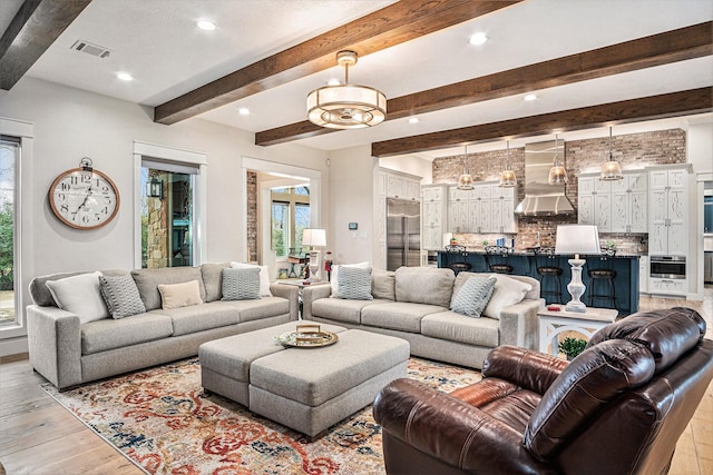 living room with beam ceiling, light wood-type flooring, visible vents, and recessed lighting