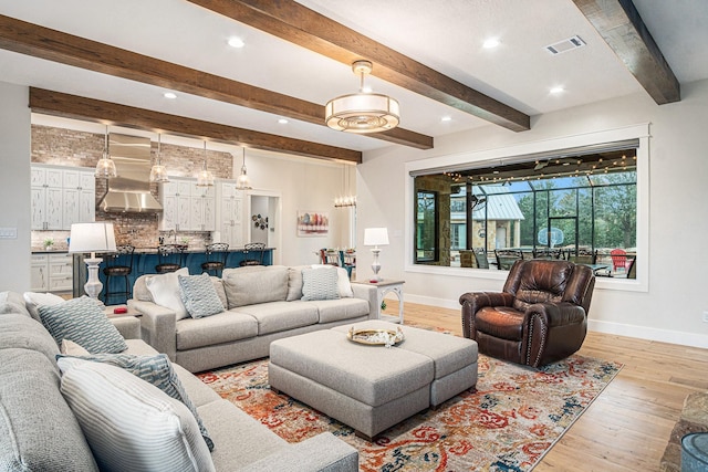 living area featuring light wood-style flooring, recessed lighting, visible vents, baseboards, and beamed ceiling