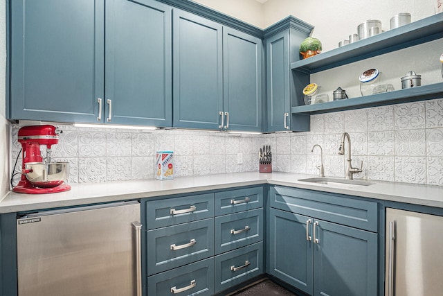 kitchen featuring blue cabinets, backsplash, stainless steel refrigerator, and a sink