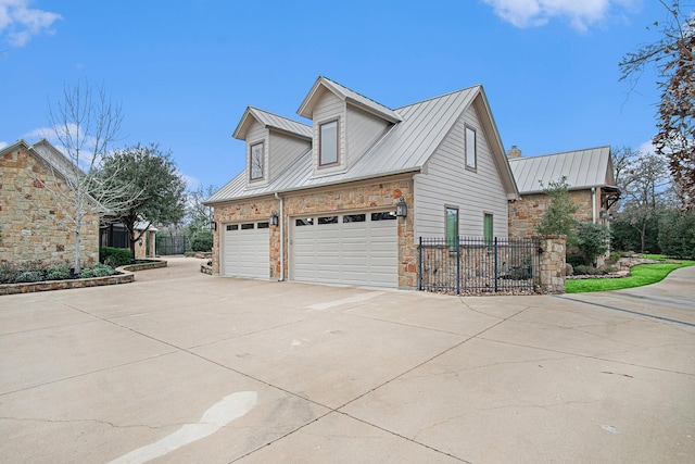 view of property exterior with driveway, a garage, stone siding, metal roof, and a standing seam roof