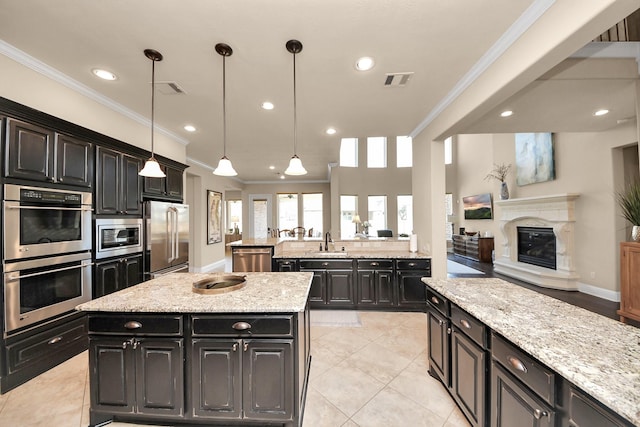 kitchen featuring visible vents, a sink, appliances with stainless steel finishes, a fireplace, and dark cabinets