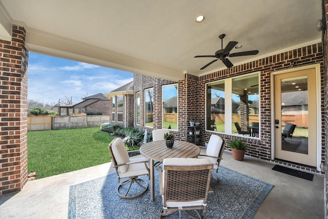 view of patio with outdoor dining space, fence, and ceiling fan