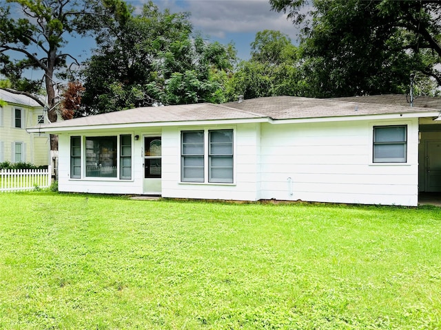 back of house featuring fence and a lawn