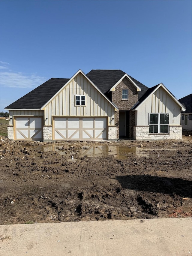 modern inspired farmhouse with board and batten siding, stone siding, and a garage