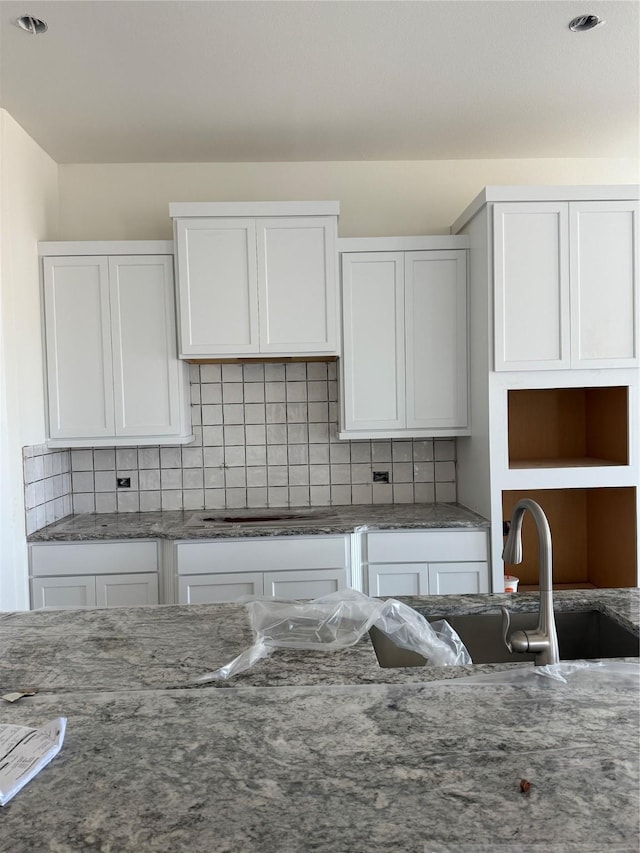 kitchen featuring stone counters, white cabinetry, and backsplash