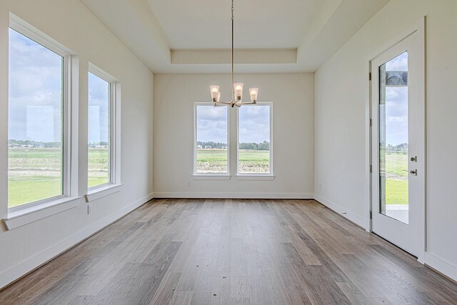 209 Peninsula Point Dr, Montgomery, TX 77356 - unfurnished dining area featuring baseboards, wood finished floors, an inviting chandelier, and a raised ceiling