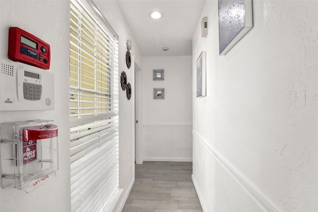 hall with wood finished floors and a textured wall