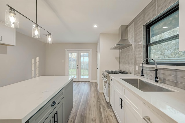 2111 Nina Lee Ln, Houston, TX 77018 - kitchen with tasteful backsplash, stainless steel range, a sink, light wood-style floors, and wall chimney range hood