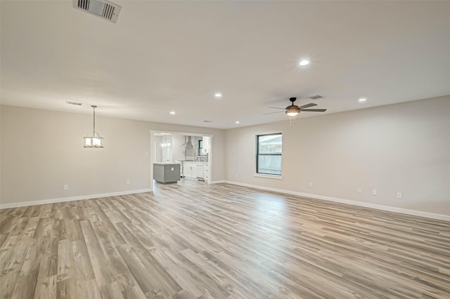 2111 Nina Lee Ln, Houston, TX 77018 - unfurnished living room featuring ceiling fan with notable chandelier, visible vents, light wood-style floors, and baseboards
