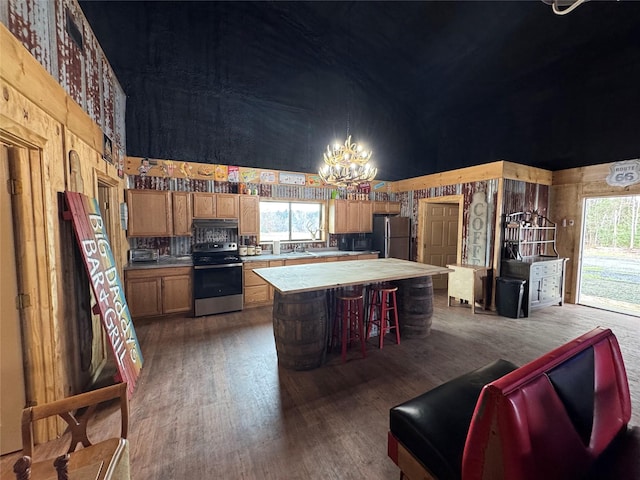 kitchen featuring a chandelier, under cabinet range hood, stainless steel appliances, a kitchen island, and wood finished floors