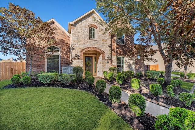 view of front of property with stone siding, brick siding, fence, and a front lawn