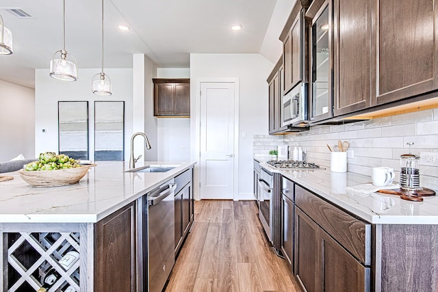 187 Peninsula Point Dr, Montgomery, TX 77356 - kitchen featuring a sink, stainless steel appliances, light wood finished floors, light stone counters, and glass insert cabinets