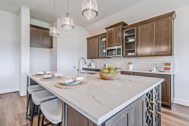 187 Peninsula Point Dr, Montgomery, TX 77356 - kitchen featuring stainless steel microwave, a sink, baseboards, light wood-type flooring, and backsplash