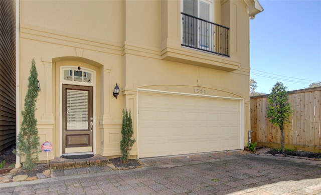 property entrance featuring stucco siding, a garage, and fence