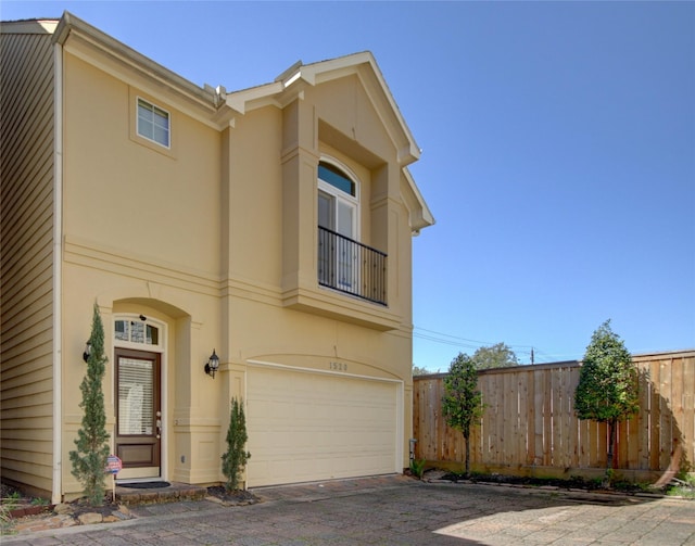 view of front of house with stucco siding, a garage, and fence