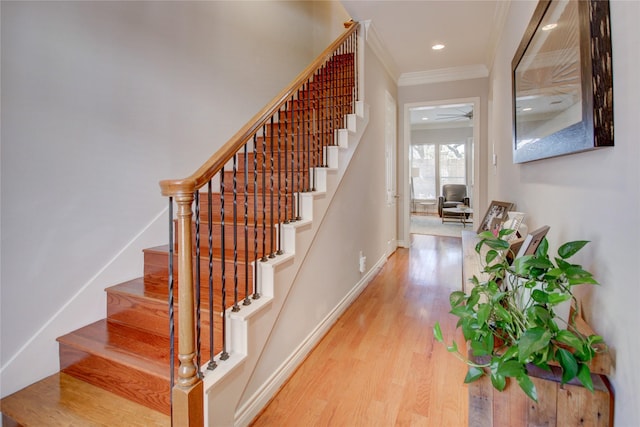 stairs with wood finished floors, baseboards, recessed lighting, ceiling fan, and crown molding