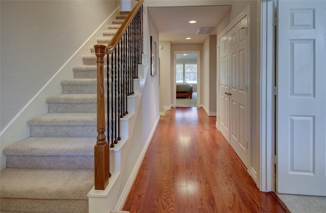 interior space with wood finished floors, visible vents, baseboards, recessed lighting, and stairs