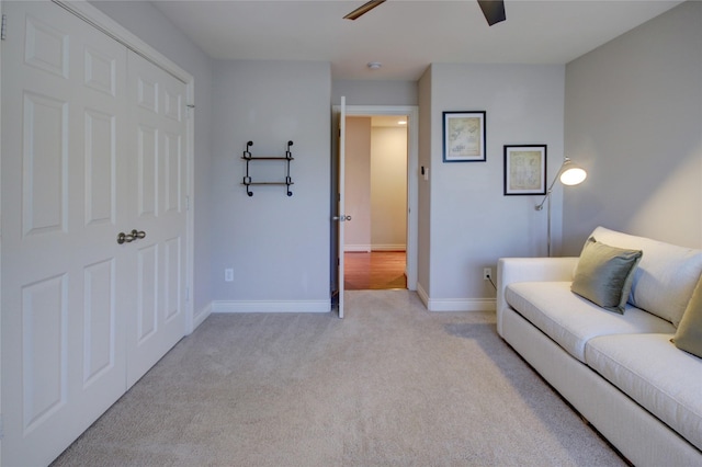 living area with a ceiling fan, baseboards, and light carpet